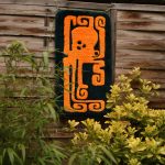 photo d'un tapis tufté avec un motif de poulpe orange, accroché à une palissade derrière des feuillages